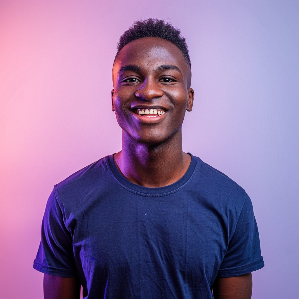 A photo of an attractive young black man with short hair, smiling at the camera, wearing a dark blue t-shirt. He is standing in front of a gradient background that transitions from light purple to pink. The lighting should be soft and even, highlighting his features without harsh shadows or reflections. His expression radiates confidence and warmth, adding depth to the overall composition. --ar 128:109