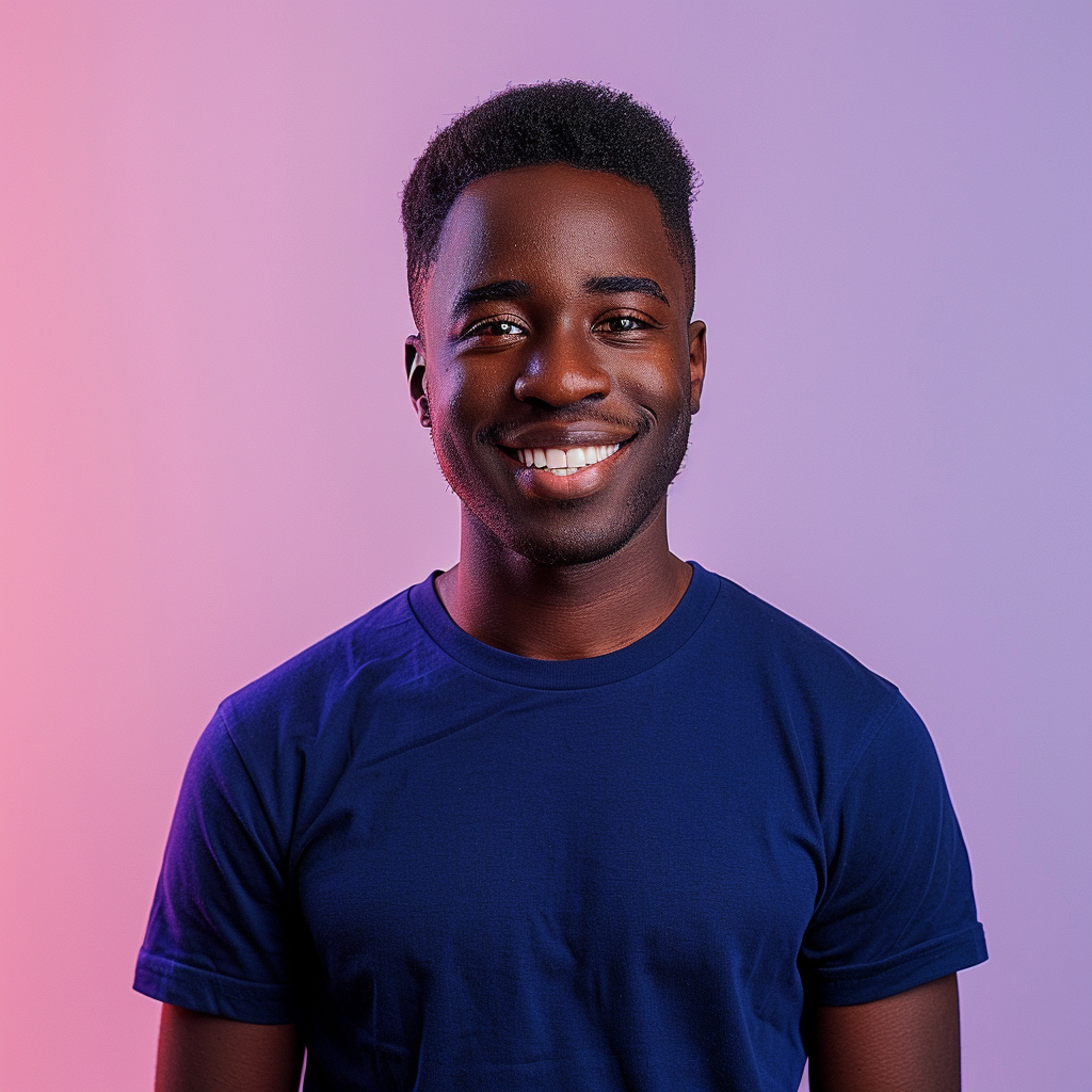 A photo of an attractive young black man with short hair, smiling at the camera, wearing a dark blue t-shirt. He is standing in front of a gradient background that transitions from light purple to pink. The lighting should be soft and even, highlighting his features without harsh shadows or reflections. His expression radiates confidence and warmth, adding depth to the overall composition. --ar 128:109